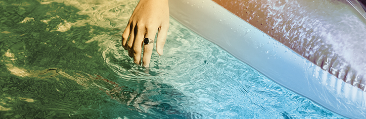 mão com anel no dedo anelar passando sobre a água em piscina