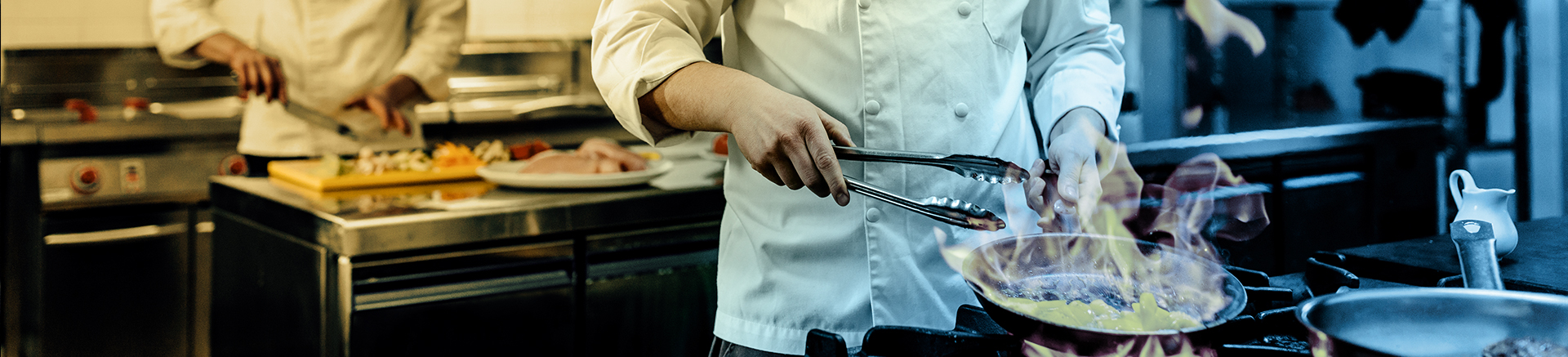 cozinheiro manipulando uma frigideira e segurando uma espátula de macarrão